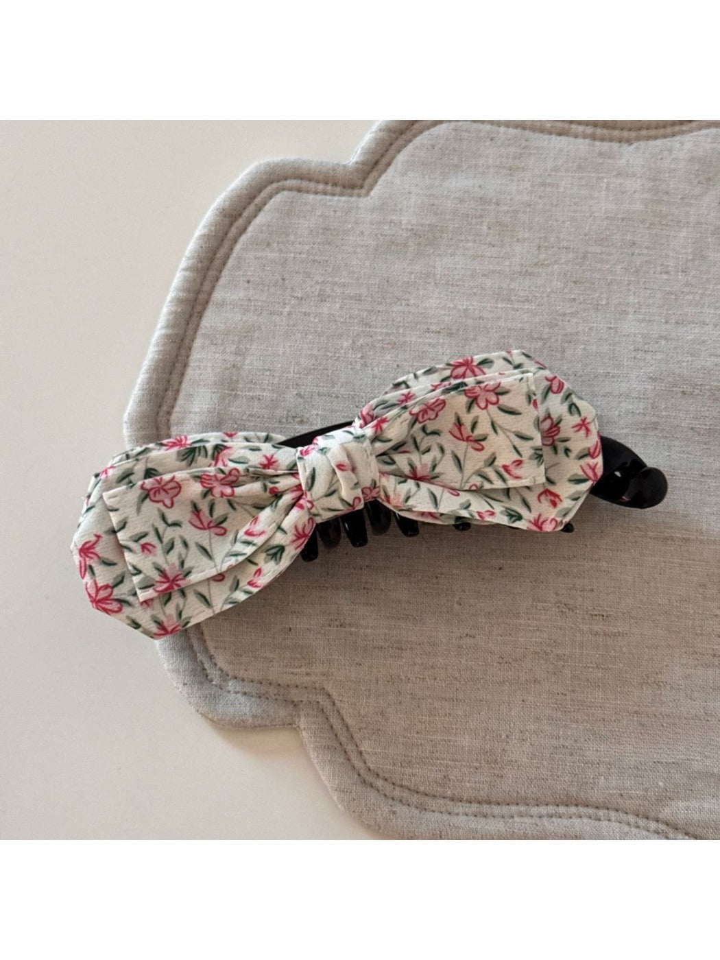 Beau bow hair clip held in hand, showing clip mechanism and painted fabric detail