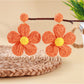 Earedge flower shaped knitted earrings hanging from a jewelry stand