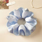Blue satin scrunchie worn on a wrist as a stylish accessory