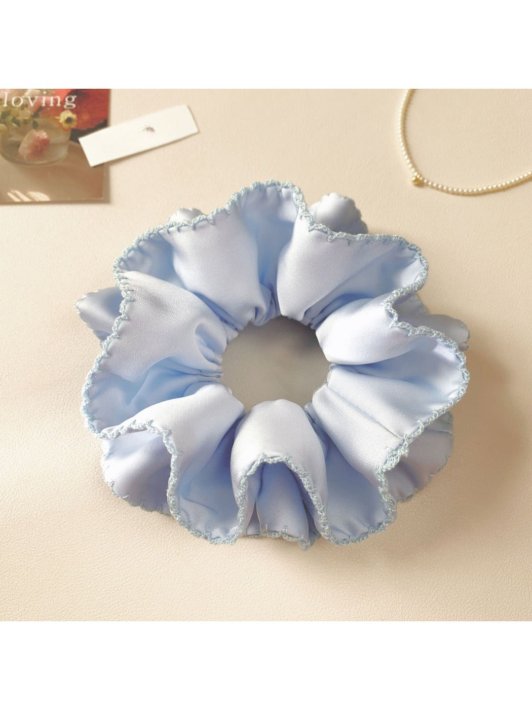 Blue satin scrunchie worn on a wrist as a stylish accessory