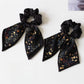 Gifty printed bow hair tie displayed on a wooden surface showing fabric texture
