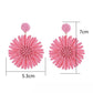 Side view of a single raffia woven sunflower earring showing texture and weave details