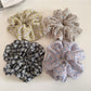 Gifty daisy print scrunchie styled on a model's wrist with casual outfit