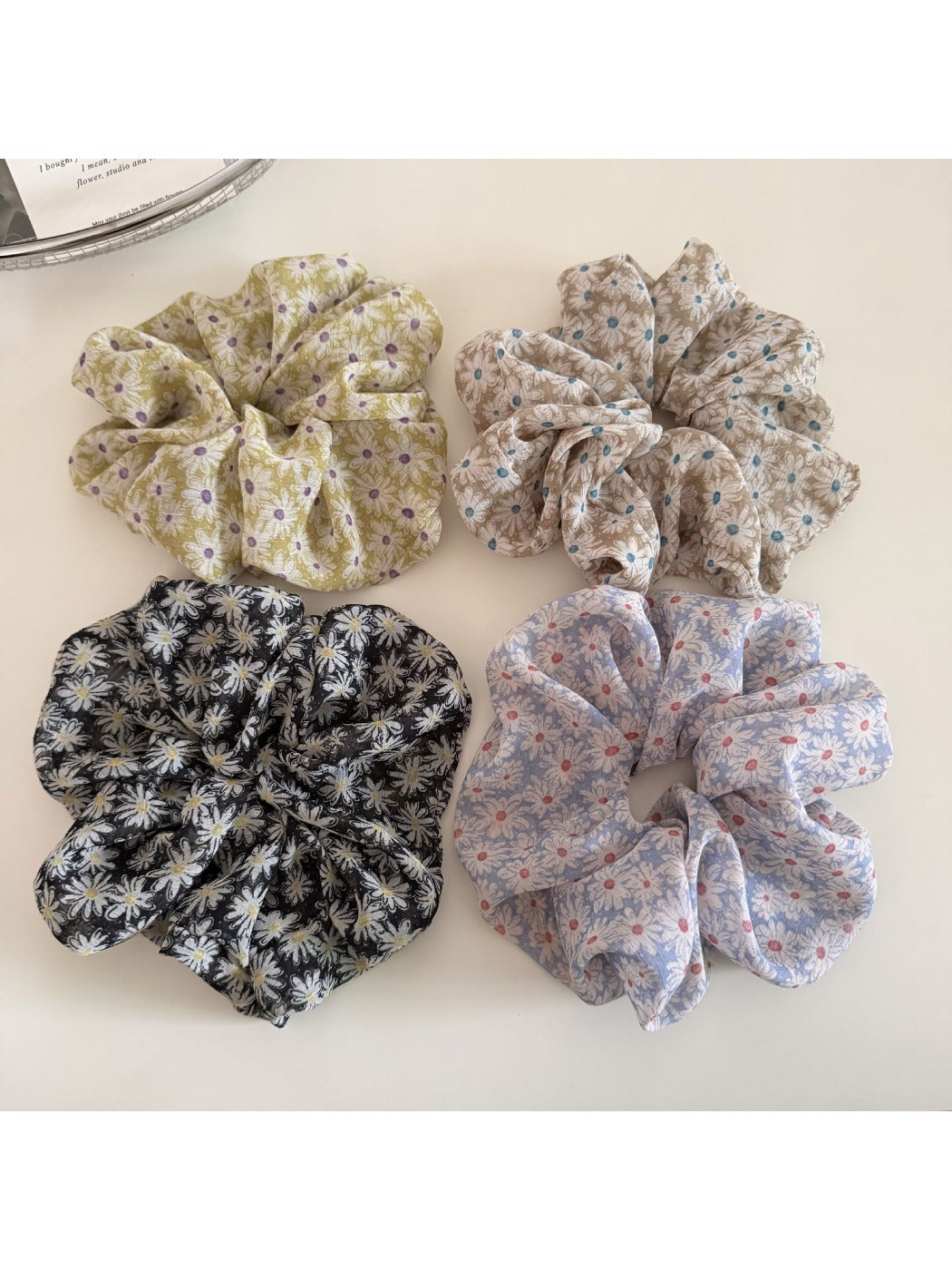 Gifty daisy print scrunchie styled on a model's wrist with casual outfit