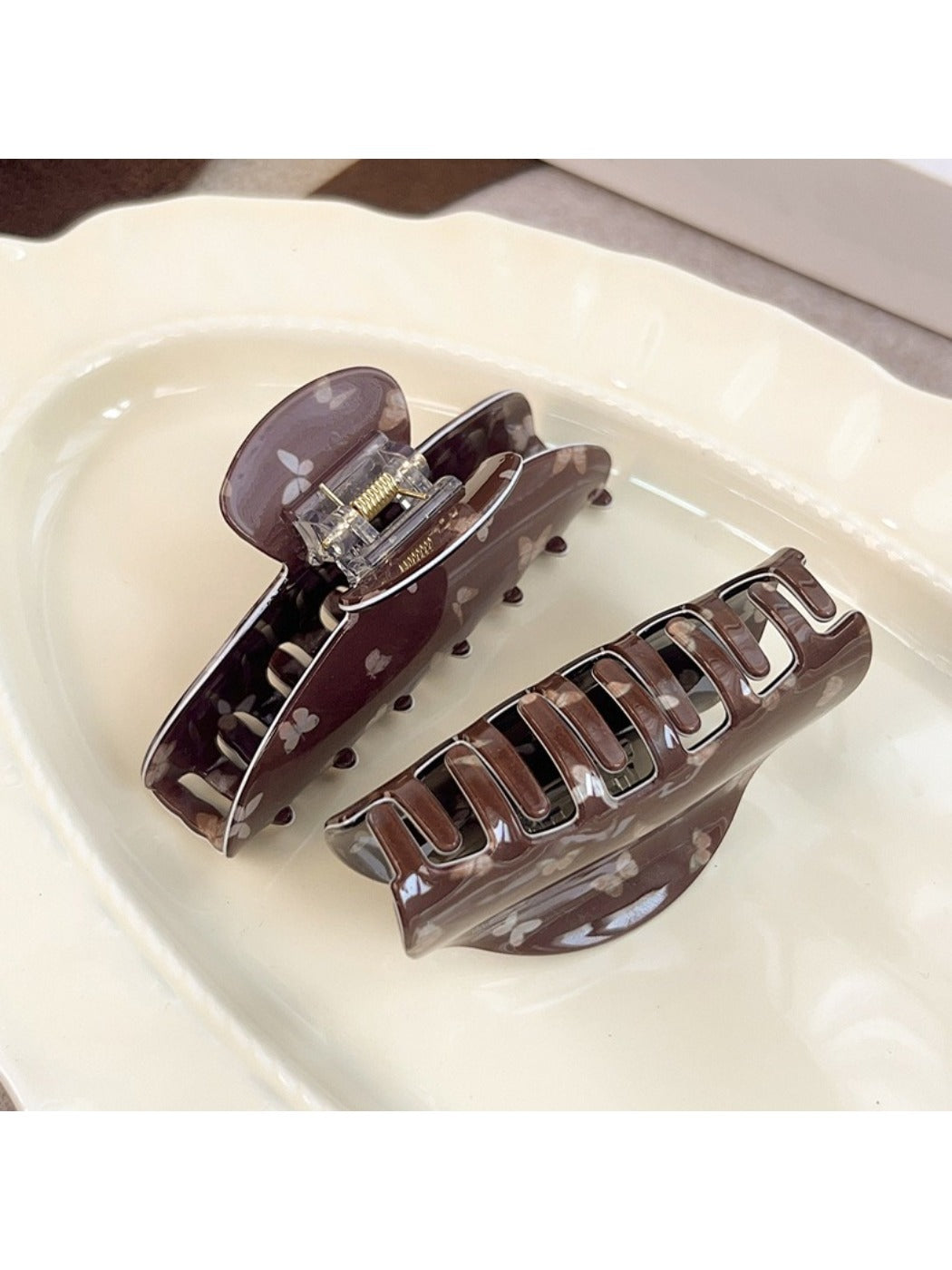 Beau claw clip open, displaying inner teeth and butterfly print