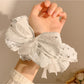 Gifty scrunchie worn on wrist highlighting lace bow and floral design