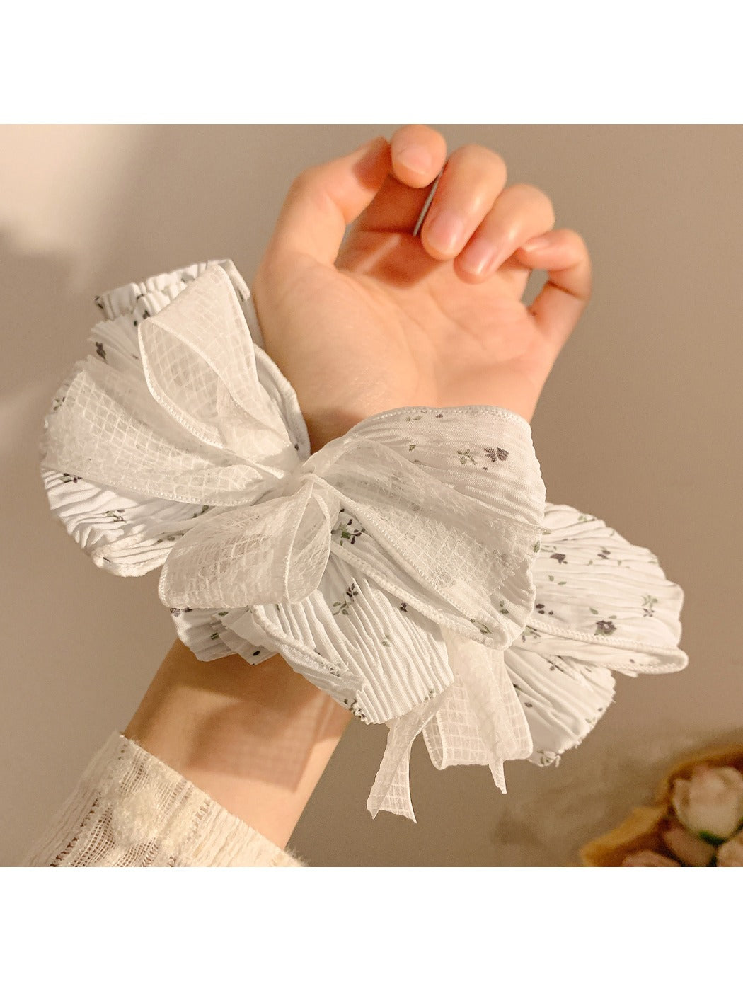 Gifty scrunchie worn on wrist highlighting lace bow and floral design