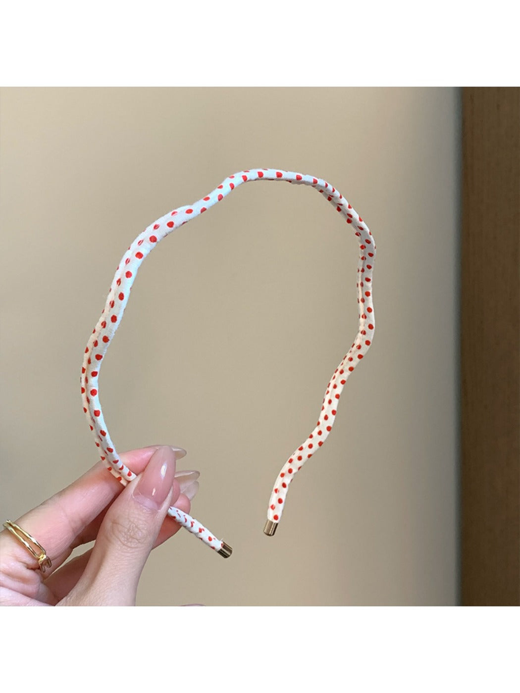 Side view of thin wavy headband with black polka dots on white background