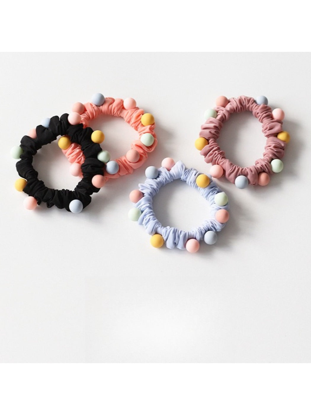 Close-up of colorful beaded hair ties arranged in a circle on a white background
