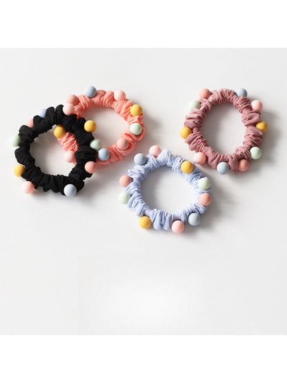 Close-up of colorful beaded hair ties arranged in a circle on a white background