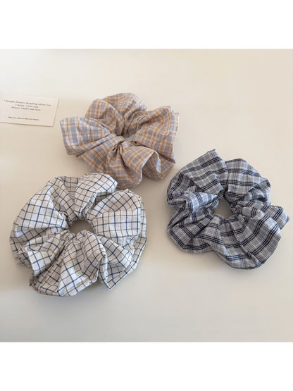 Gifty minimalist plaid scrunchie displayed on a wooden surface with soft lighting