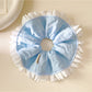 White scrunchie with blue ruffle detail on a plain background