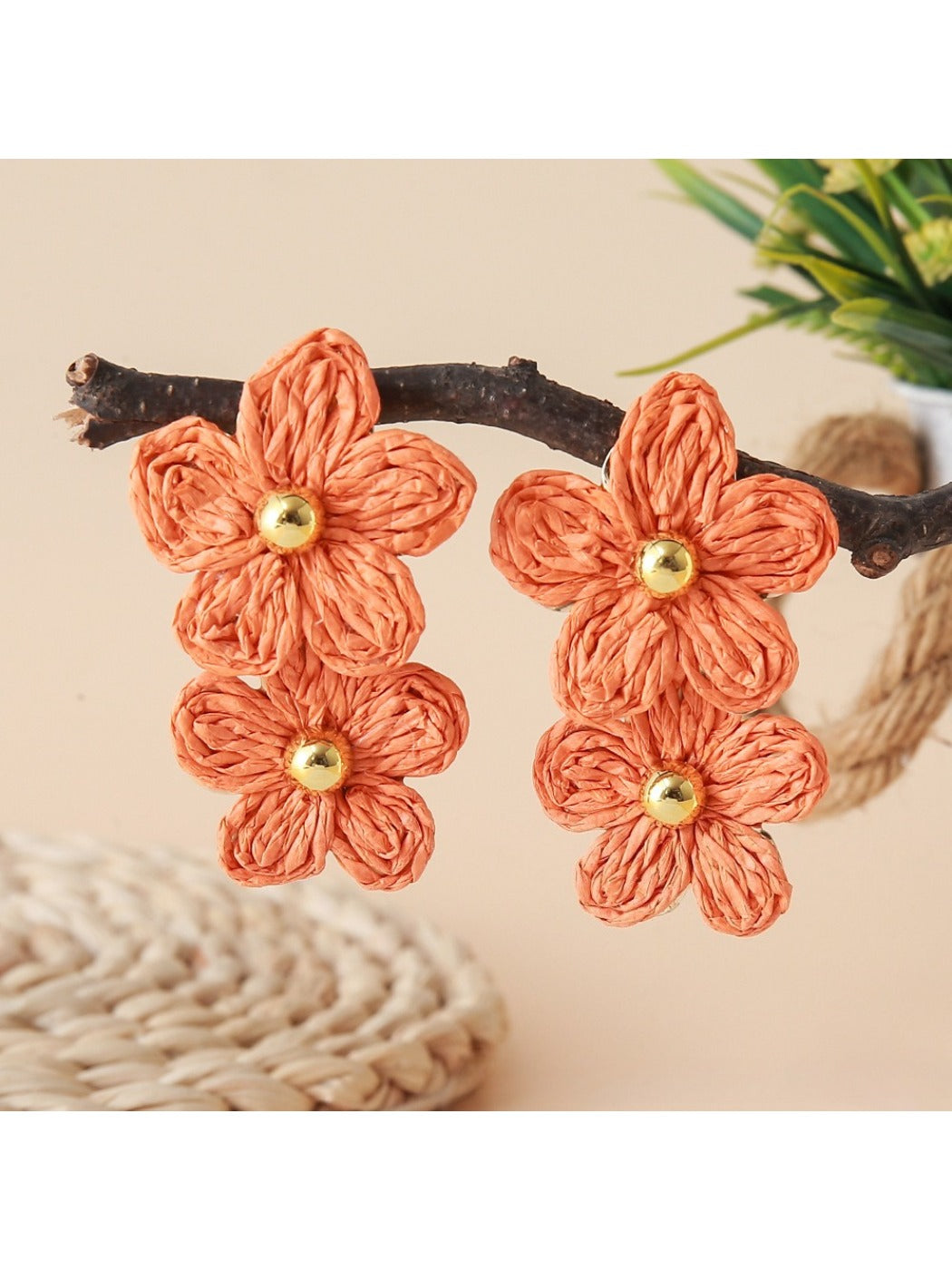 Pair of raffia flower shaped earrings placed on textured fabric surface