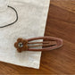 Beau flower pattern hair clip angled to show thickness and clasp mechanism