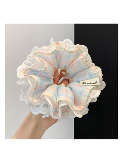 Blue plaid lace trim scrunchie styled on a wrist with soft lighting
