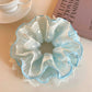 Blue lace scrunchie wrapped around a ponytail on a model's hair
