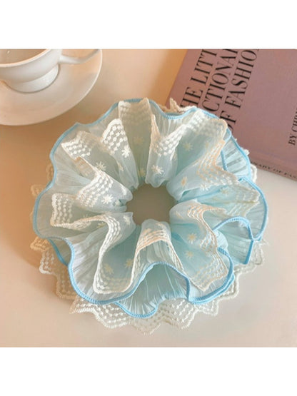 Blue lace scrunchie wrapped around a ponytail on a model's hair