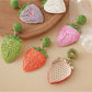 Pair of earedge raffia strawberry earrings displayed on a white background