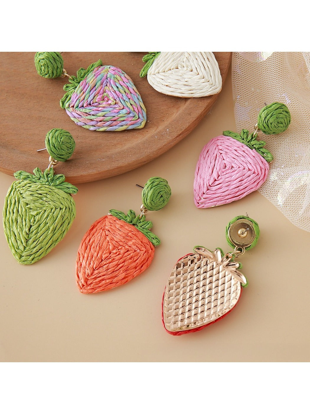 Pair of earedge raffia strawberry earrings displayed on a white background