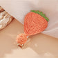 Beau raffia strawberry flower hair clip displayed with matching accessories