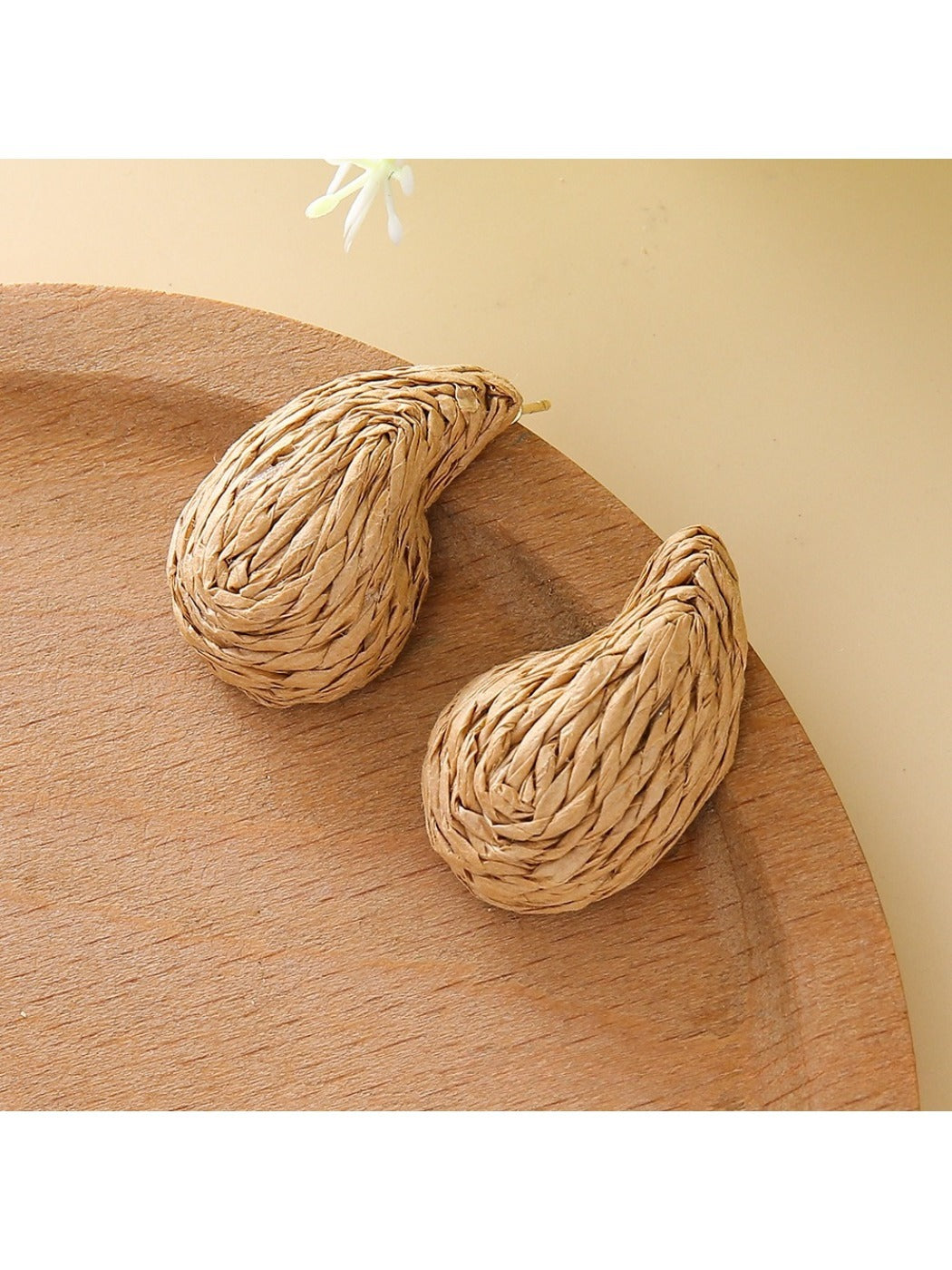 Earedge raffia water drop shaped stud earrings worn on a model's ear