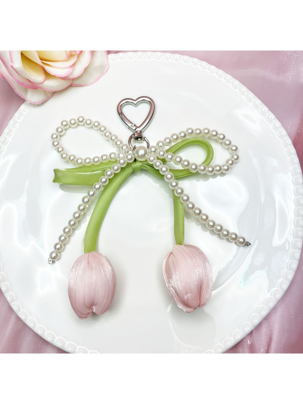 Minimalist bow and tulip pendant keychain displayed on a wooden surface