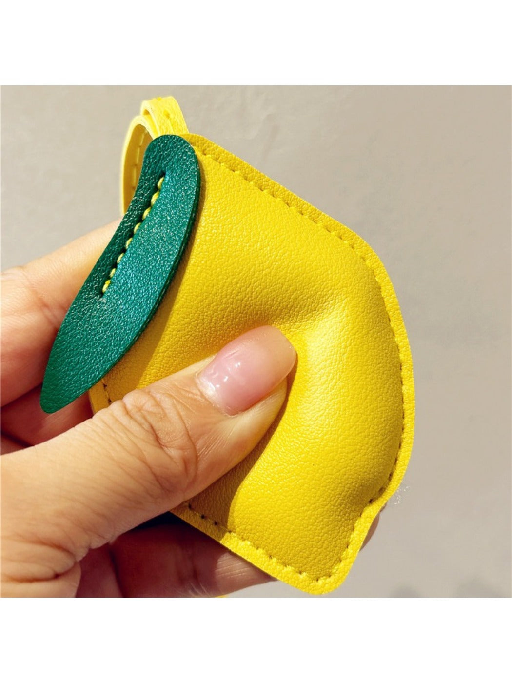 Lemon keychain placed next to a smartphone and wallet on a table