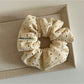 Beige scrunchie with dot cutouts displayed next to matching hair accessories