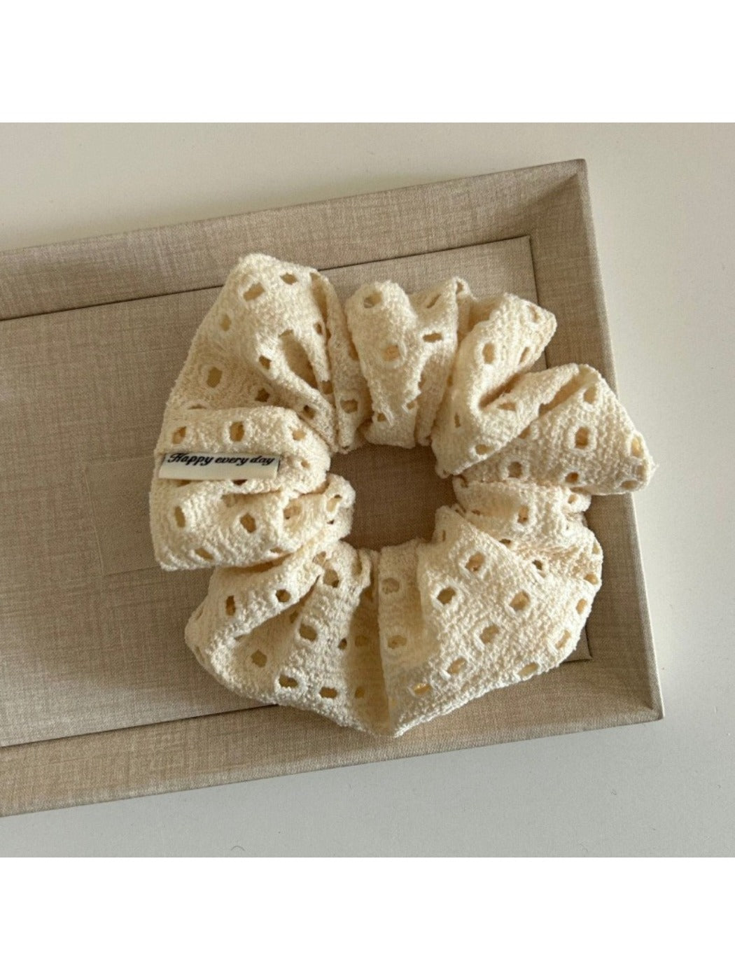 Beige scrunchie with dot cutouts displayed next to matching hair accessories