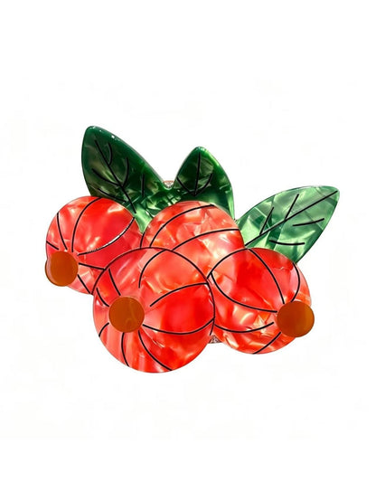 Beau hair clip with orange fruit design held between fingers for size reference