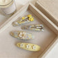 Yellow floral hair clip displayed on a white surface highlighting its curved shape