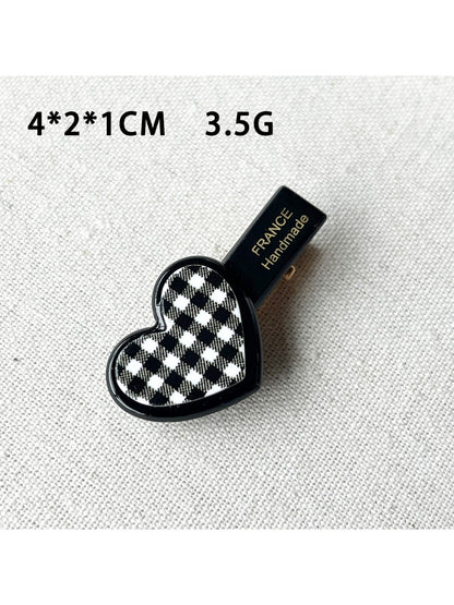 Beau flower and heart acrylic hair clip placed on a wooden surface