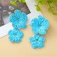 Earedge floral pendant raffia drop earrings displayed on a wooden surface