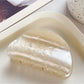 Beau macaron colored claw clip resting on a fabric surface