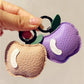 Side view of small apple keychain highlighting its rounded shape and metal loop