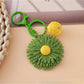Multiple sunflower keychains arranged in a row on a flat surface