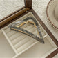 Beau triangle claw clip resting on white surface, side angle