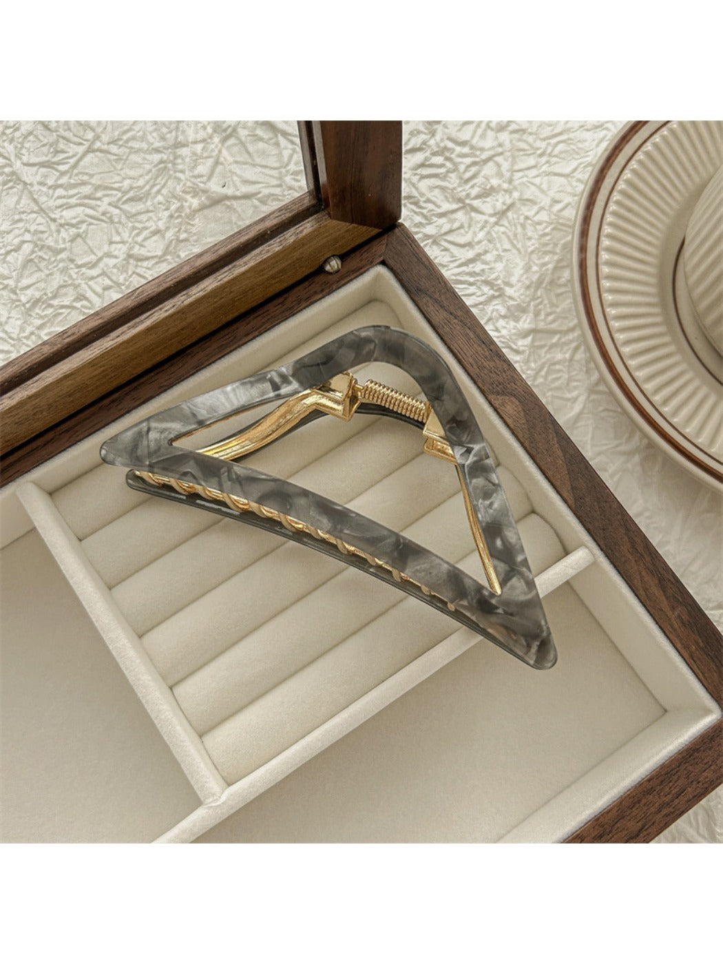 Beau triangle claw clip resting on white surface, side angle