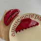 Beau red fashion hair clip shown from side angle highlighting curved design