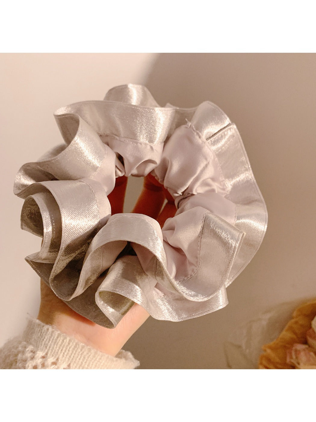 Gifty satin ruffle scrunchie in cream color placed on a marble surface