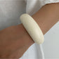 Lovra wide round bangle bracelet shown in natural light to highlight its reflective surface