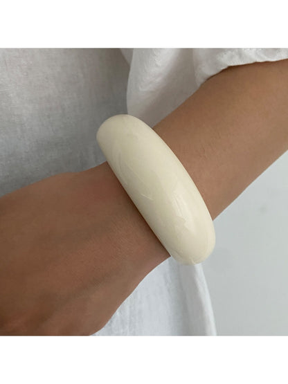 Lovra wide round bangle bracelet shown in natural light to highlight its reflective surface