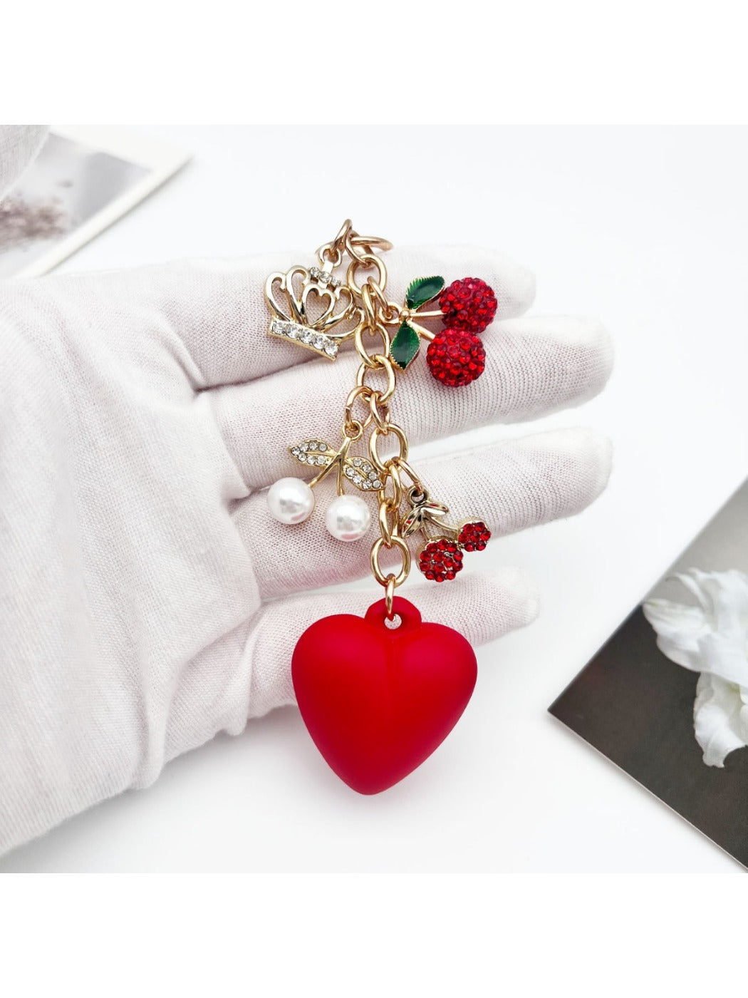 Cherry heart charm keychain attached to a gold keyring with a white backdrop