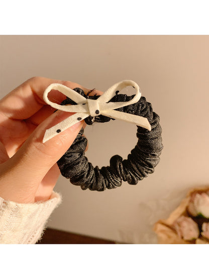 Vintage polka dot bow hair tie in black and white on a plain background