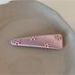 Pink bow hair clip displayed on a flat surface with a shadow