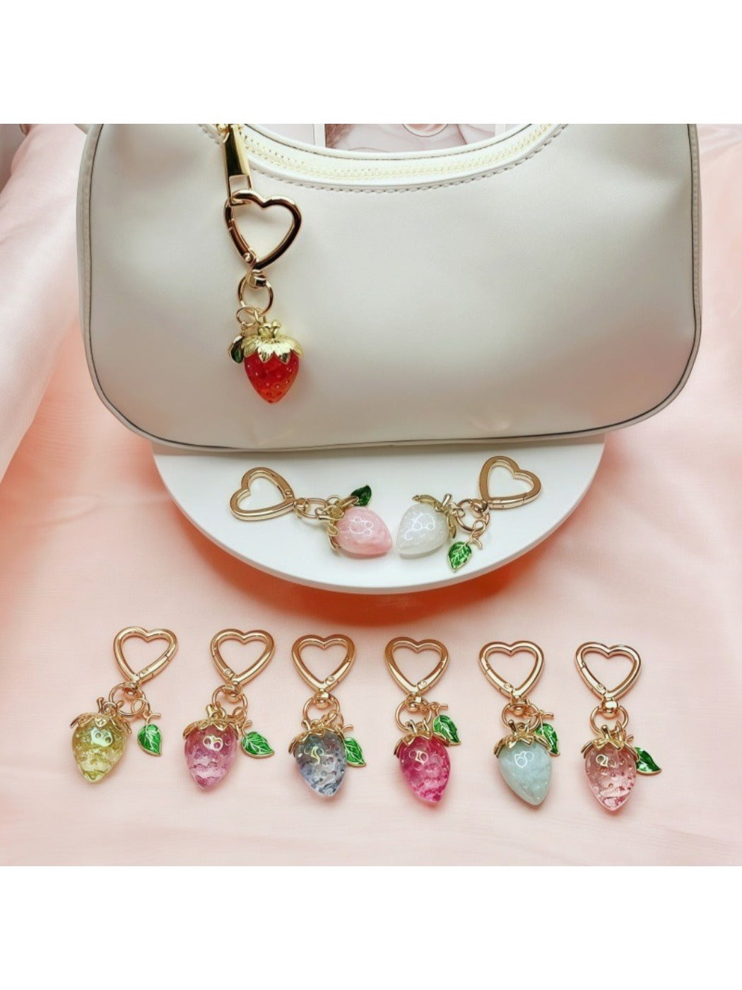 Keypus strawberry charm keychain displayed on a pink fabric background