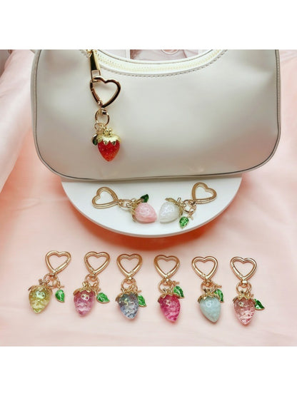 Keypus strawberry charm keychain displayed on a pink fabric background