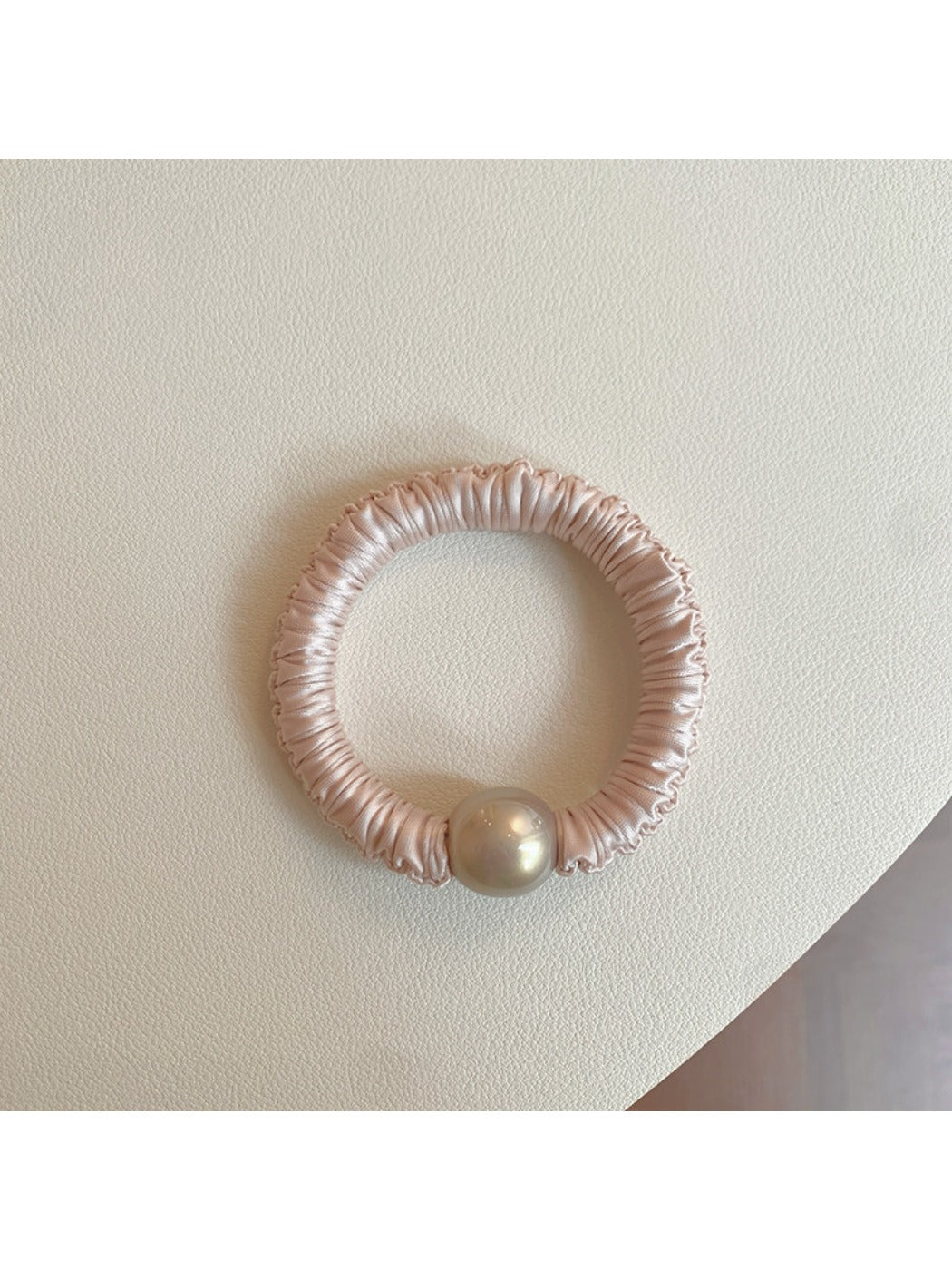 Pink mini scrunchie held in hand showing its small size and elasticity