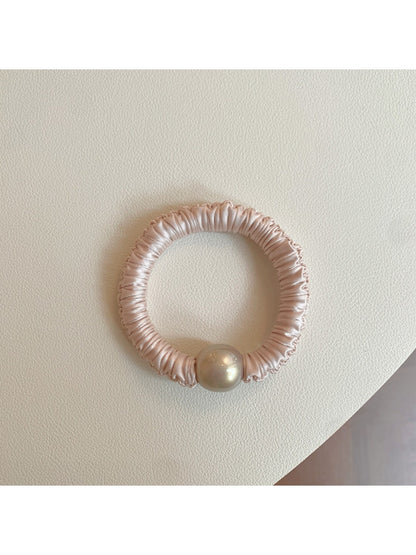 Pink mini scrunchie held in hand showing its small size and elasticity