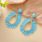 Earedge raffia teardrop hollow earrings hanging on a jewelry stand